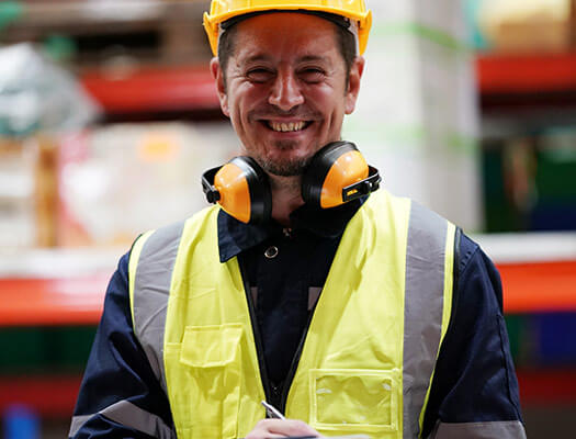 Colaborador de BSáenz sonriendo dentro de bodega de mercancías de clientes, listos para enviarse por servicios de logística